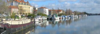 Vue panoramique Roanne, rivière calme, bateaux à quai, journée ensoleillée.